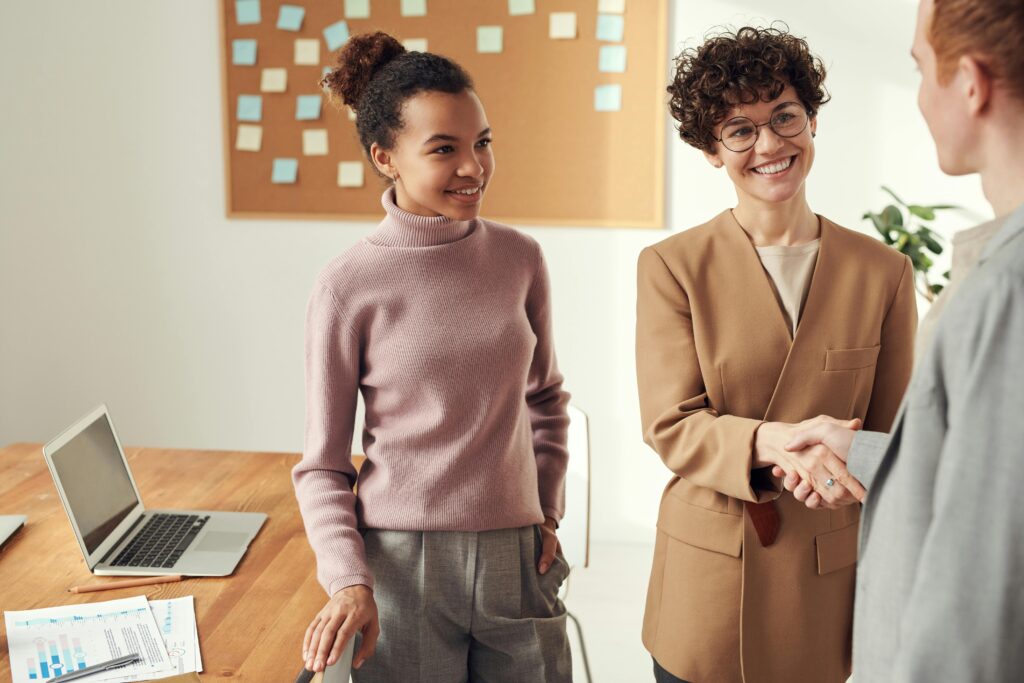pexels-photo-3184301-3184301 Business colleagues in an office shaking hands and smiling, showcasing teamwork and collaboration.